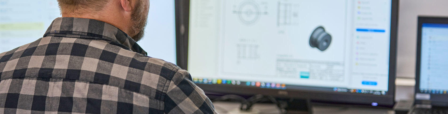 A technical employee is looking at a technical drawing of a plastic machine part on his computer. 
