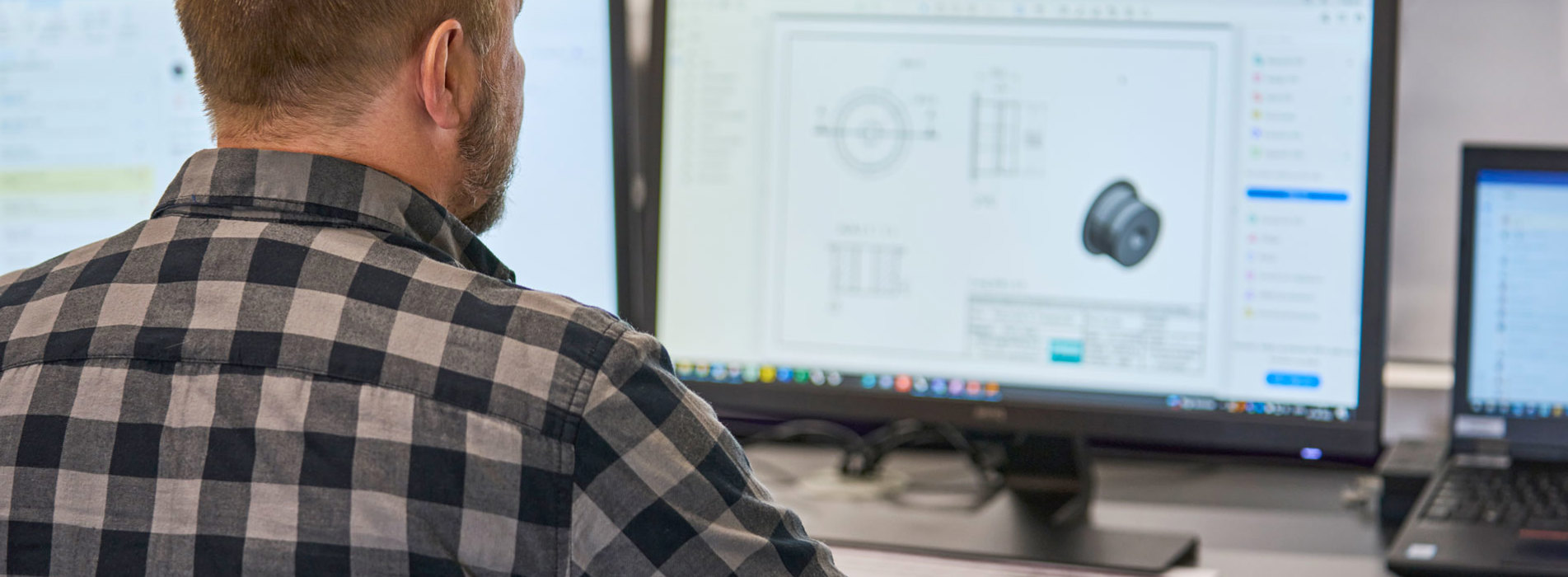 En teknisk medarbejder tjekker en teknisk tegning af en plast maskindel på sin computer. 