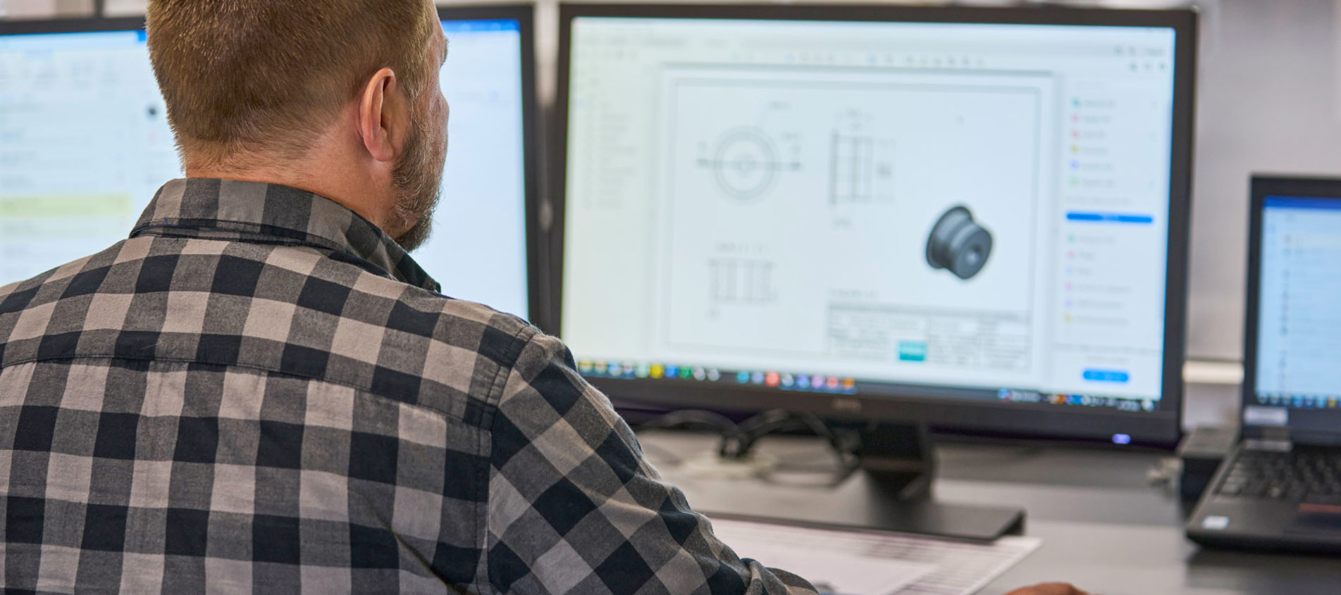 En teknisk medarbejder tjekker en teknisk tegning af en plast maskindel på sin computer. 