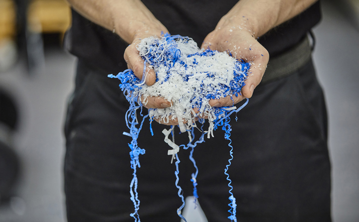 Hænder holder spåner fra spåntagende bearbejdning i blå og hvid