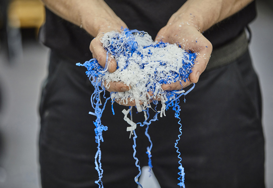 Hænder holder spåner fra spåntagende bearbejdning i blå og hvid