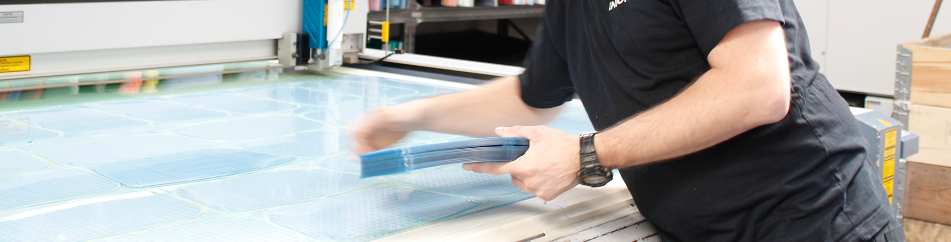 Industry technician in the laser workshop lasser cutting screens for face visors in clear PET