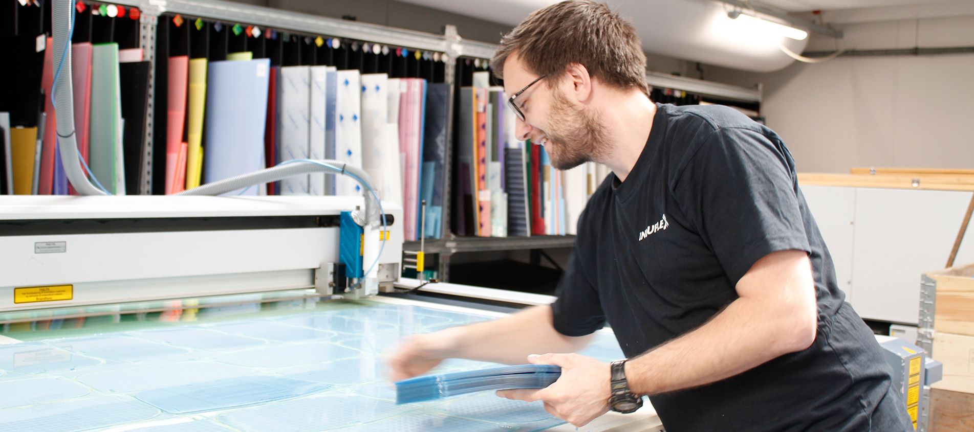 Industritekniker i laserhal laserskærer skærme til ansigtsvisirer i klar PET