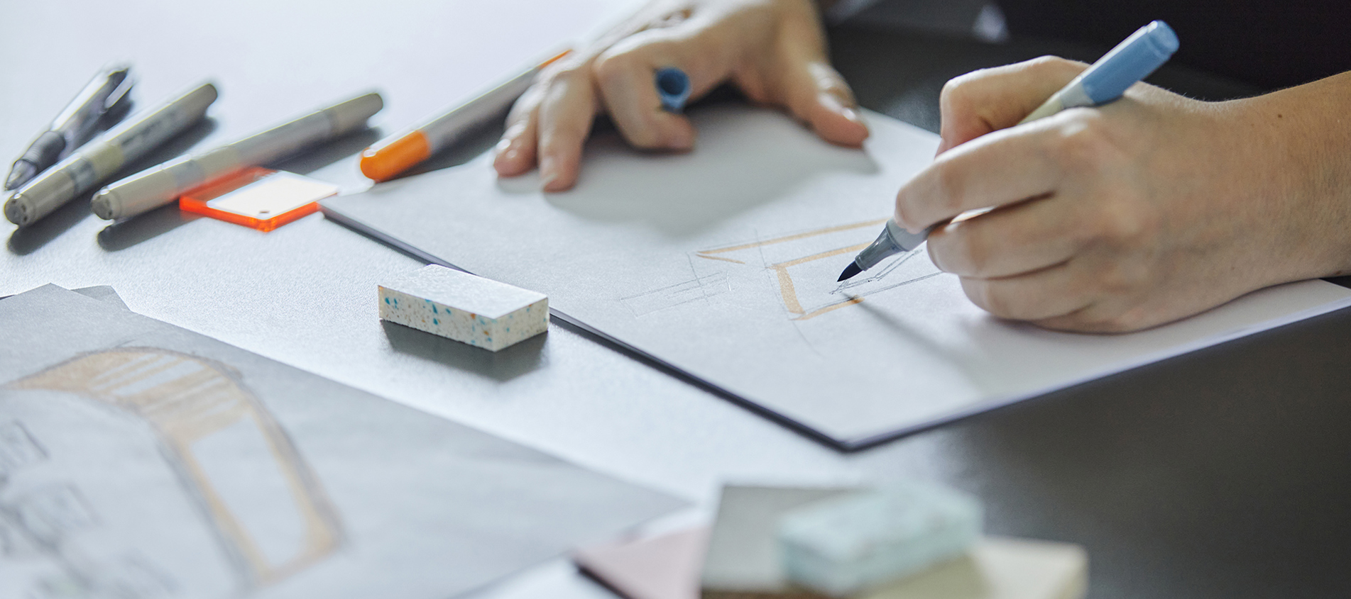 Designer tegner håndskitser af podier i plast med tusch