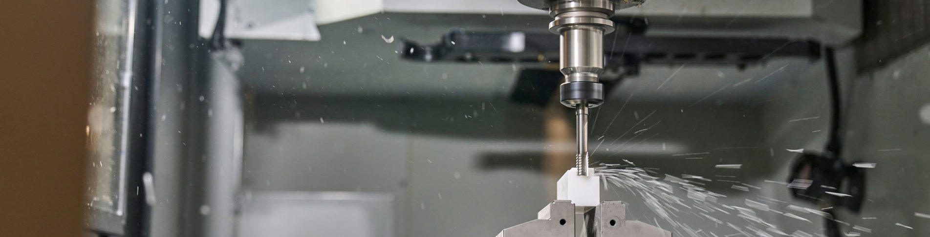 A white machine part in plastics is being milled in a five-axis milling cutter.