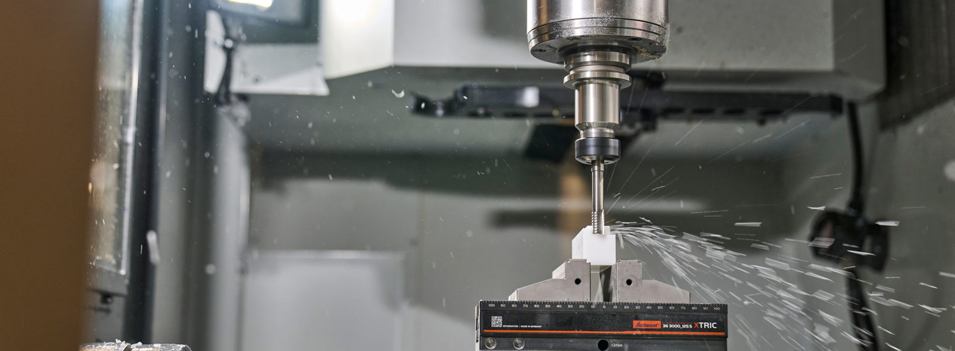 En hvid maskindel i plast fræses ud i en fem-akset fræser.