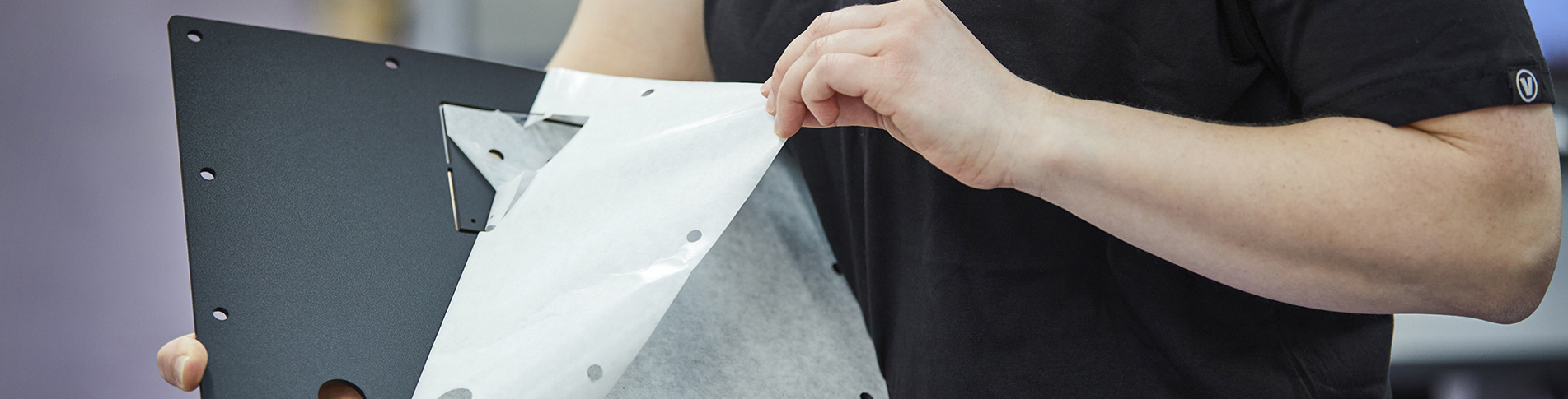 Montagemedarbejder afmonterer folie på en sort plastplade