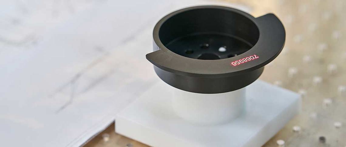 Sort drejet maskindel med lasergraverede tal på sig.