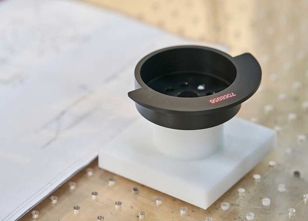 Sort drejet maskindel med lasergraverede tal på sig.