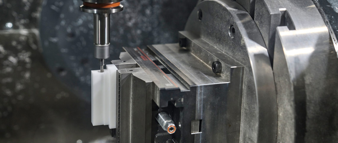 En hvid maskindel i POM fræses i en CNC-fræser.