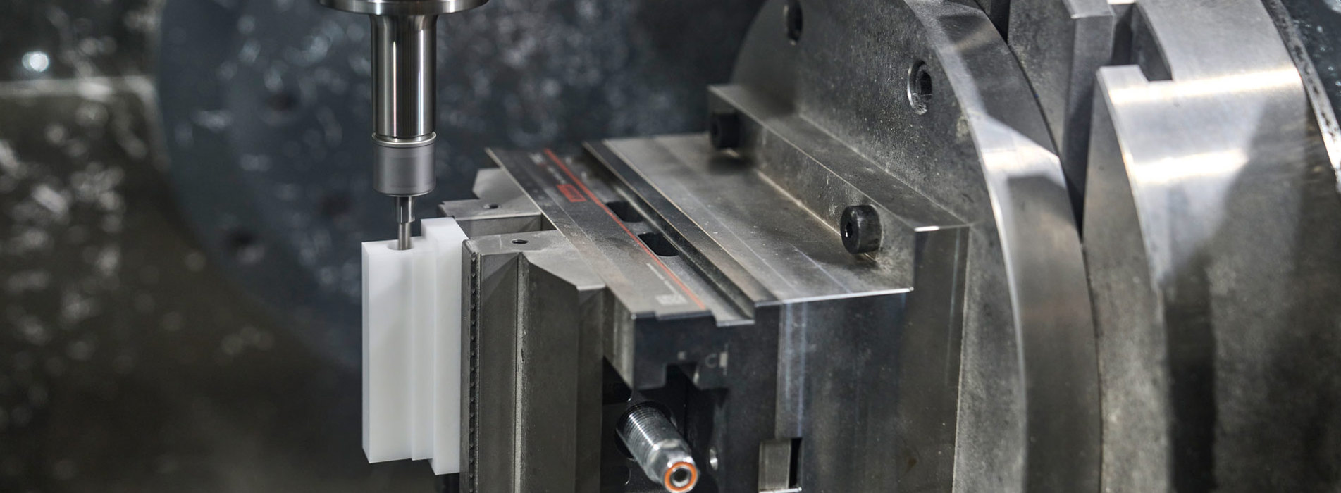 En hvid maskindel i POM fræses i en CNC-fræser.