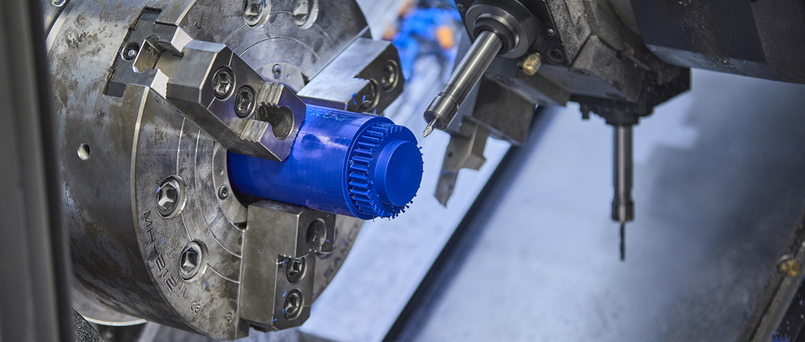CNC lathe turns a gear wheel in blue plastic with many serrations