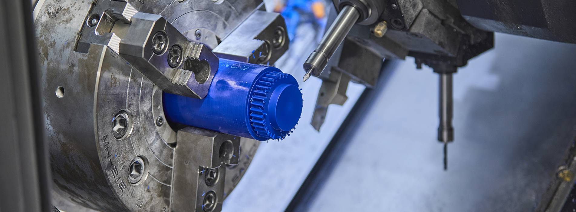 CNC-drejebænk drejer et tandhjul i blå plast med mange takker