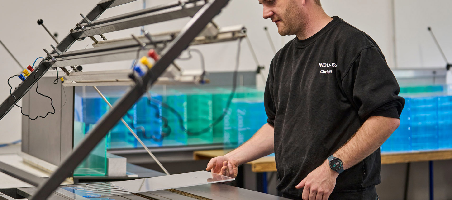 En medarbejder justerer et akrylstykke som ligger på et varmbukke-bord.