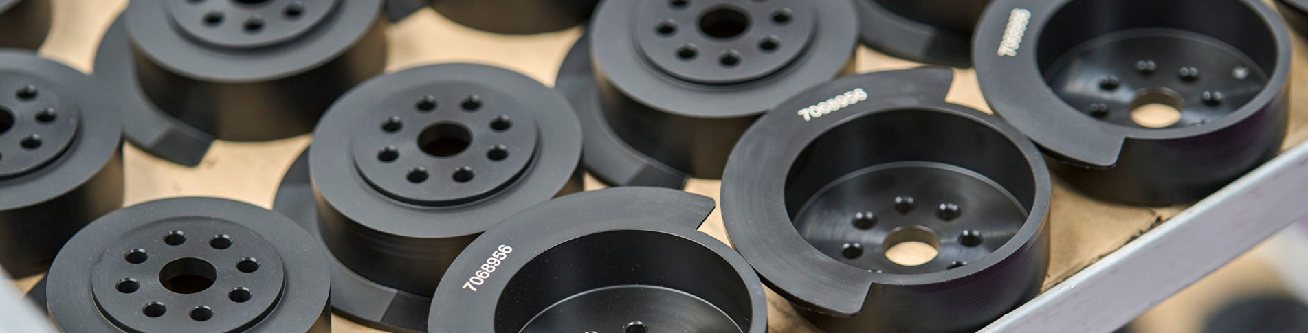 A table full of black machine parts with engraved numbers.