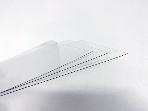 Tre tynde plader af gennemsigtig PET plast på en hvid baggrund