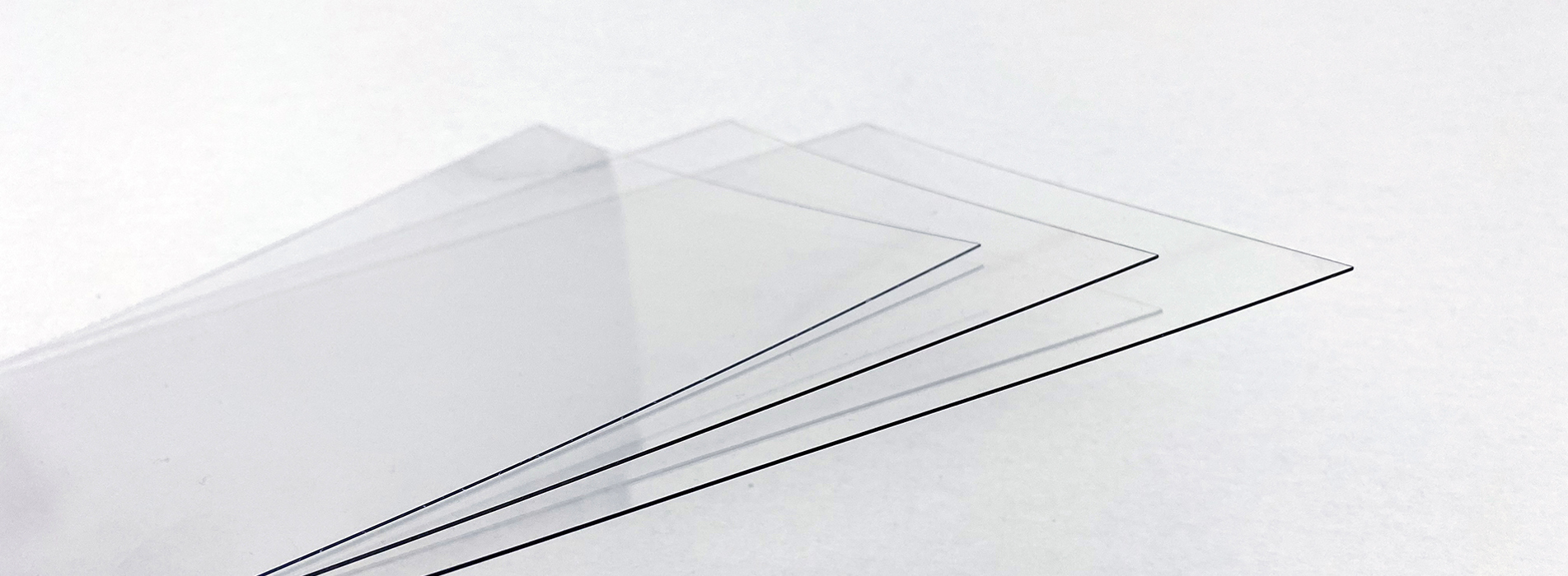 Tre tynde plader af gennemsigtig PET plast på en hvid baggrund