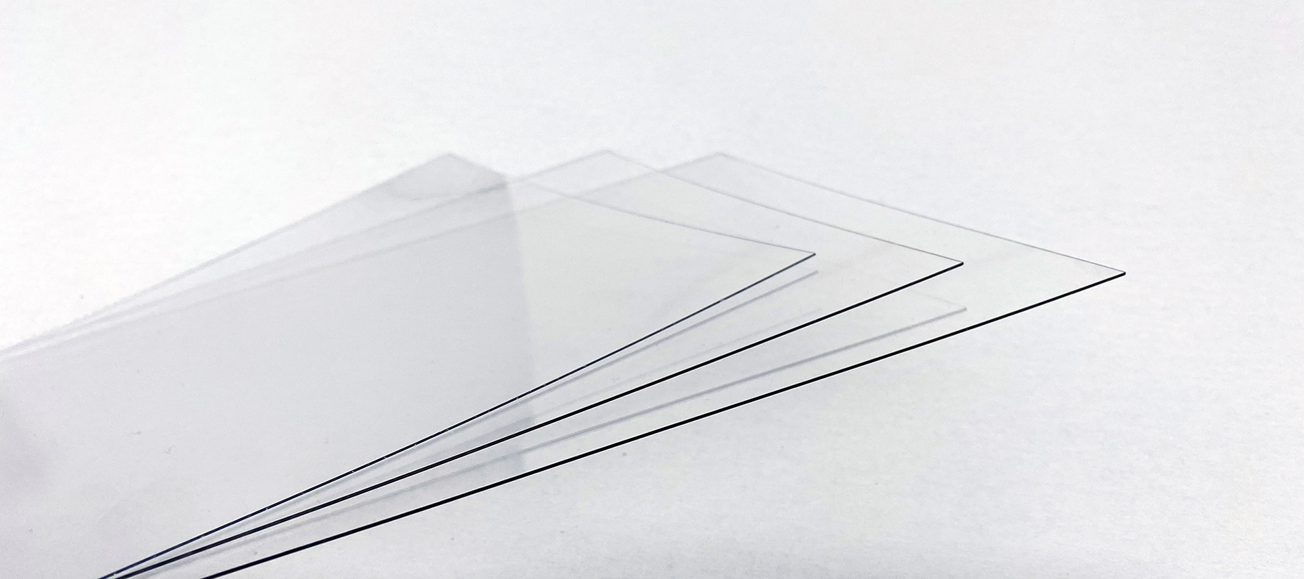 Tre tynde plader af gennemsigtig PET plast på en hvid baggrund