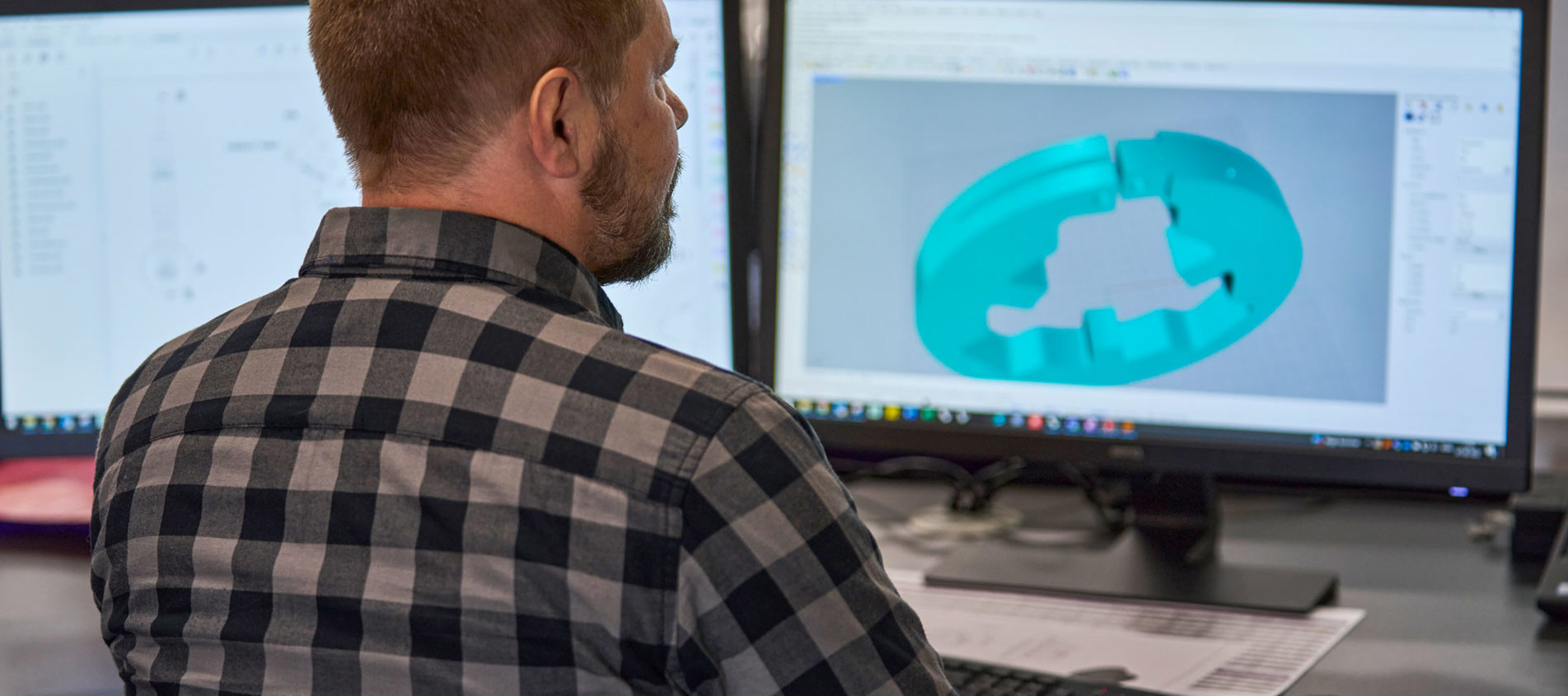 En teknisk designer finjusterer et design af en maskindel i plast på sin computerskærm.