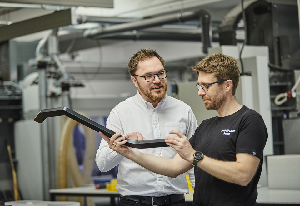 Industry technician shows Sales Manager details on a plastic part in the cutting workshop