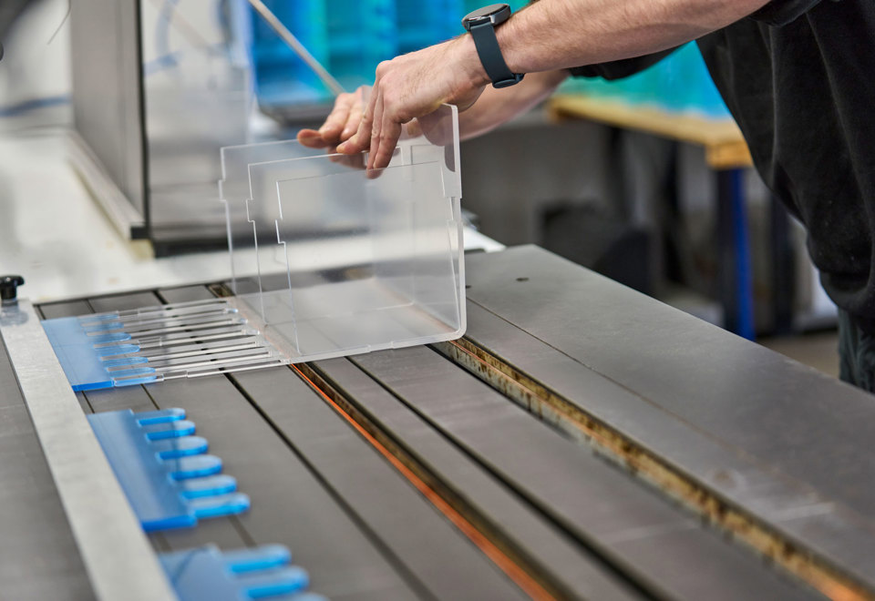En medarbejder justerer et display i akryl, som ligger på et varmbukke-bord.
