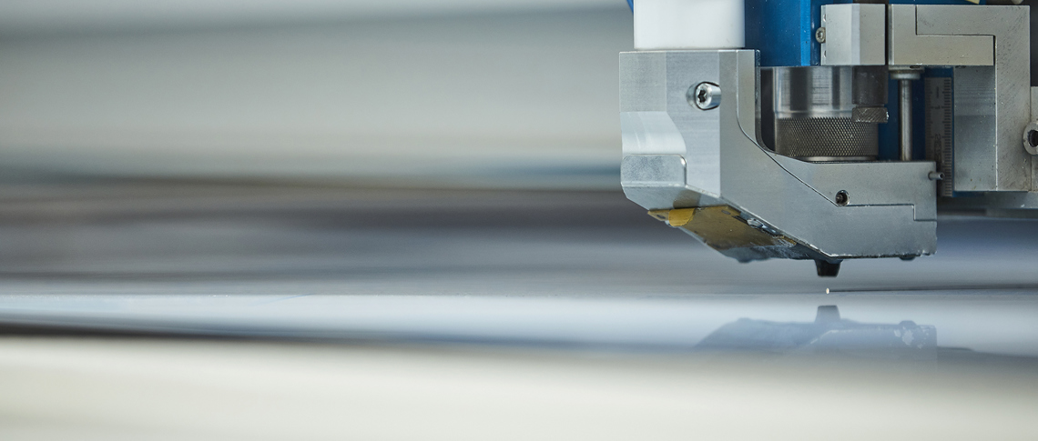 Laserskærer skærer i en plade af gennemsigtig akryl hos Induflex