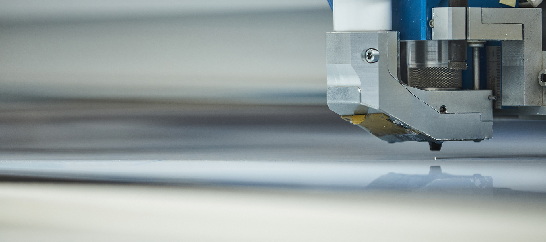 Laserskærer skærer i en plade af gennemsigtig akryl hos Induflex