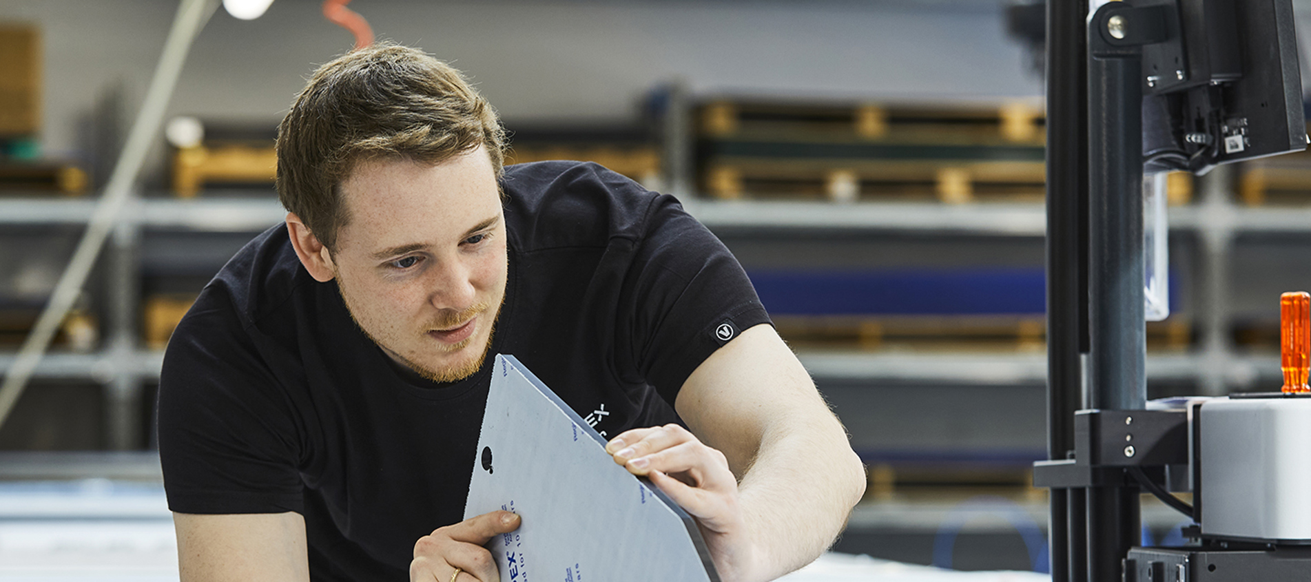 En industritekniker hos Induflex tjekker kvaliteten på snittet på et akrylemne skåret på skæreplotter