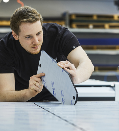 A industry technician at Induflex checks the quality of the cut on a acrylic part cut on a cutting plotter