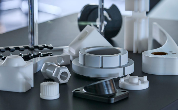 Machine parts of engineering plastics in the colours grey, white and black.
