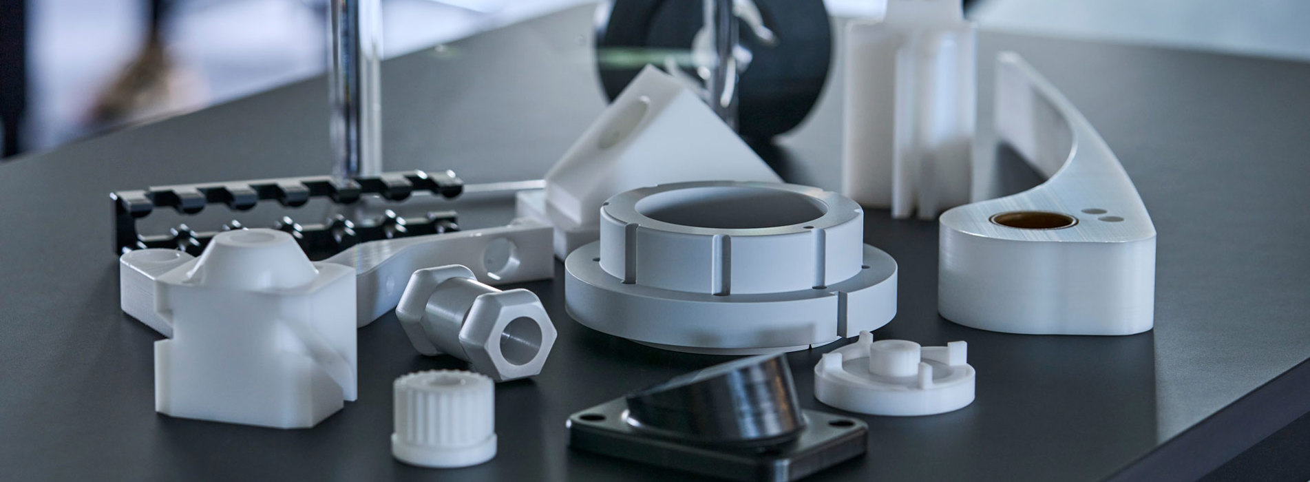 Machine parts of engineering plastics in the colours grey, white and black.