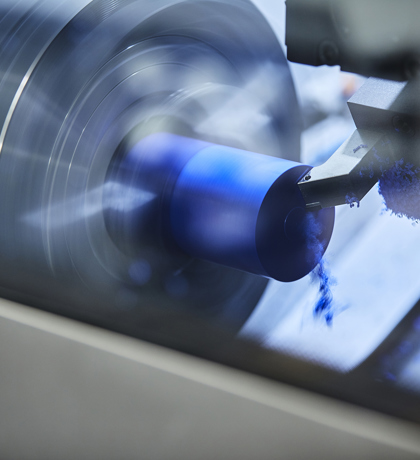 CNC lathe at Induflex's production turns a part in blue plastic