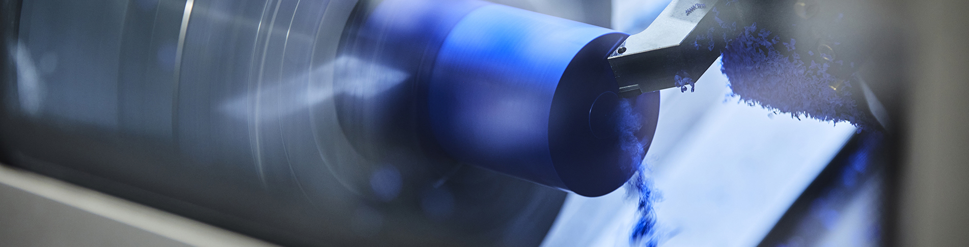 CNC lathe at Induflex's production turns a part in blue plastic