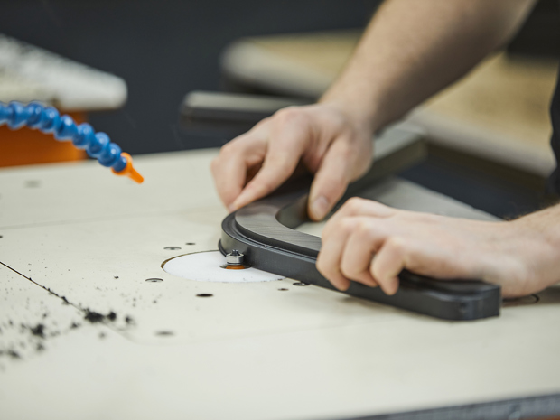 Produktionsmedarbejder hos Induflex afgrater et plastemne i sort POM