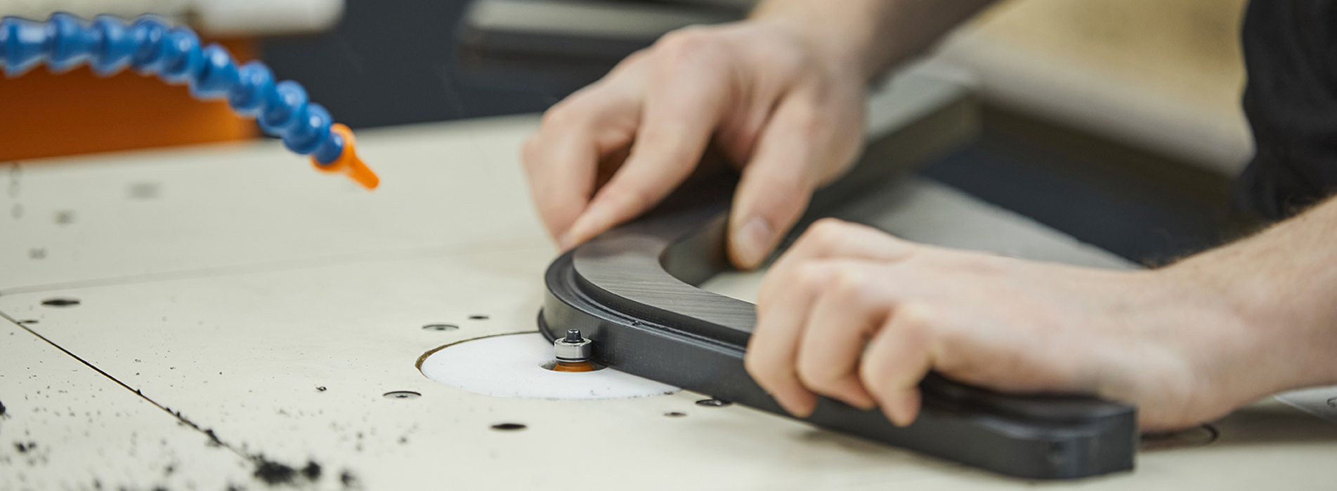 Production employee at Induflex deburring a plastic part in black POM