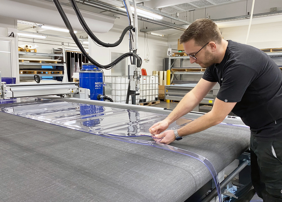 En produktionsmedarbejder tjekker en udskæring af blød PVC på en skæreplotter