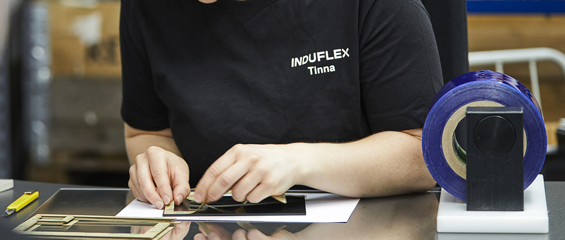 Montagemedarbejder monterer folie på et emne i montagen hos Induflex