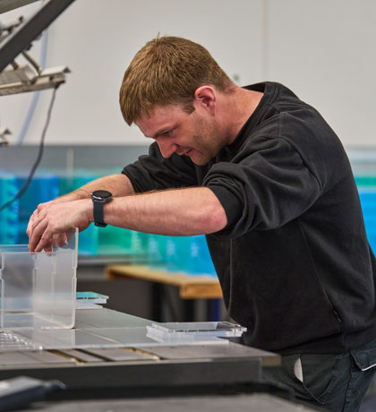 A worker heat bends an acrylic display.
