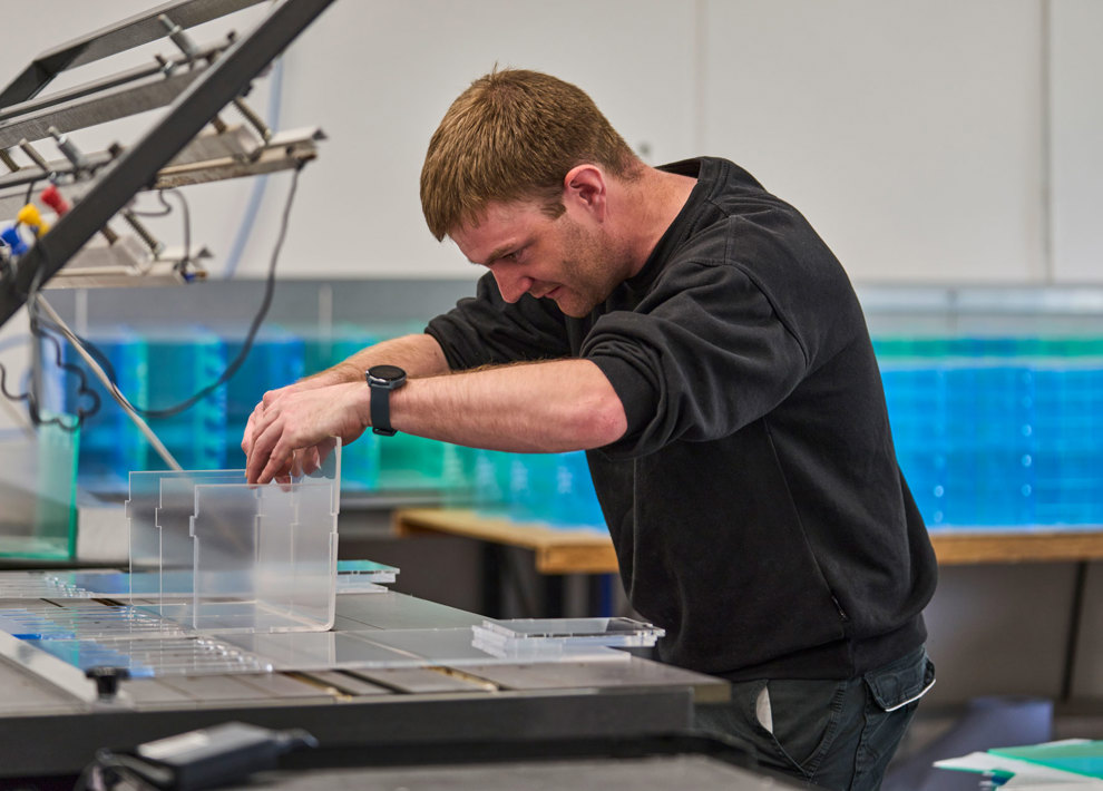 En medarbejder varmbukker et akryldisplay. 