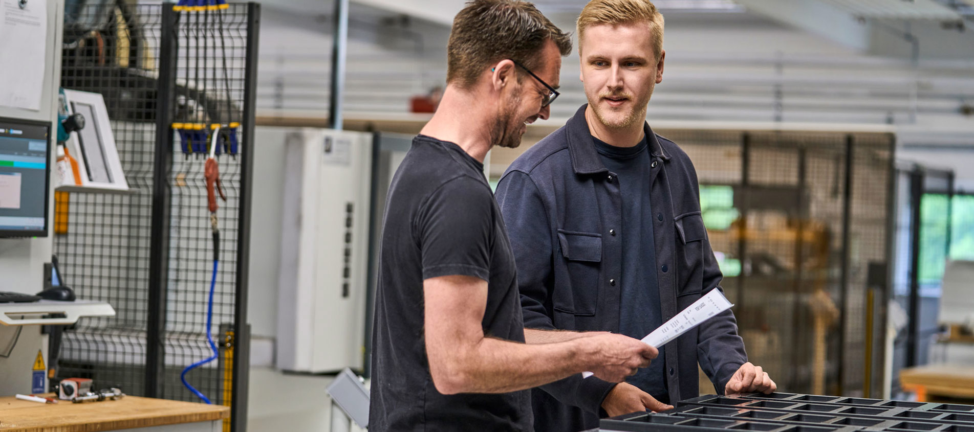 En sælger og en industritekniker tjekker et plastemne i produktionen. 